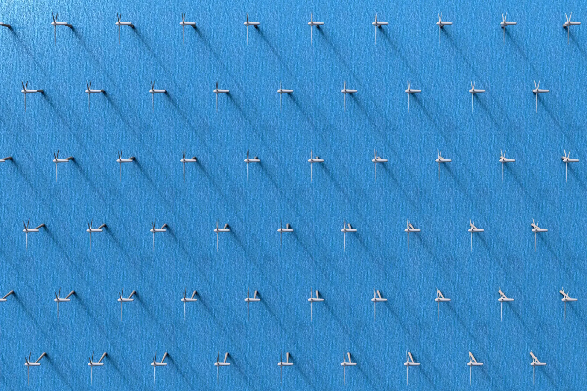 An aerial view of a large grid of white wind turbines set against a blue background, casting long shadows on the surface.