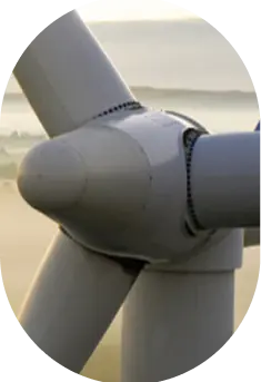 Close-up of a wind turbine blade and hub against a misty landscape background, showcasing the turbine's design and structure.