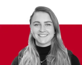 A smiling woman with long blonde hair wearing a black turtleneck, posed against a white and red background.