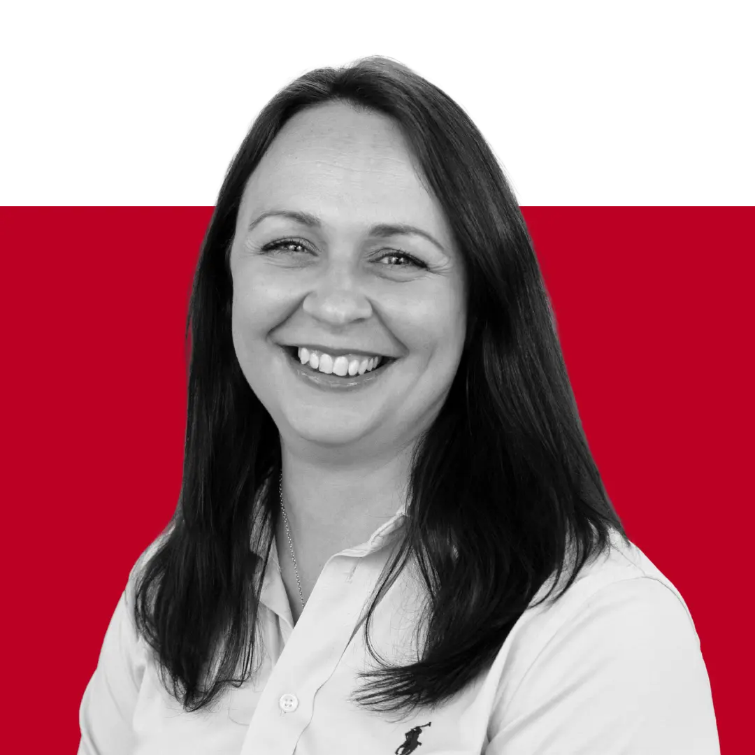 A smiling woman with long dark hair wearing a white collared shirt against a red and black background.