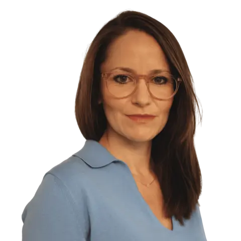 A woman with long brown hair wearing glasses, a light blue blouse, and a subtle necklace, looking confidently at the camera against a white background.