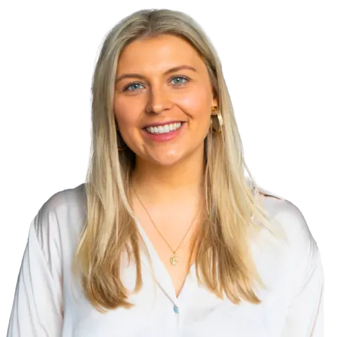 A young woman with long, light blonde hair smiling at the camera. She is wearing a white shirt and gold hoop earrings, with a necklace visible around her neck. The background is plain white.